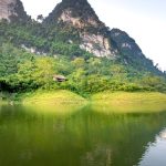 Amazing landscape of calm Na Hang lake surrounded by huge rocky mountains covered with green trees on sunny day in Tuyen Quang province
